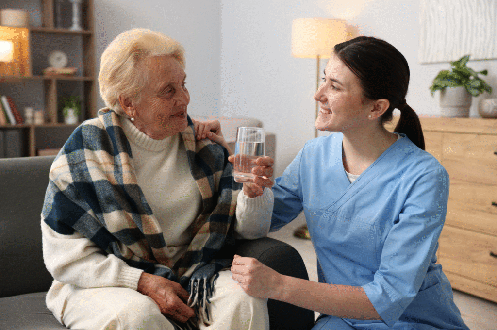 A home care worker with an elderly woman drinking a glass of water.